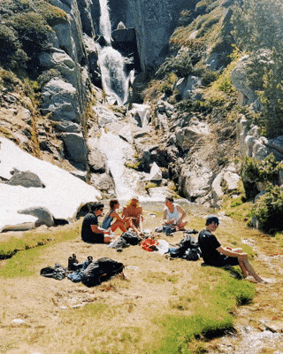 people resting near a waterfall