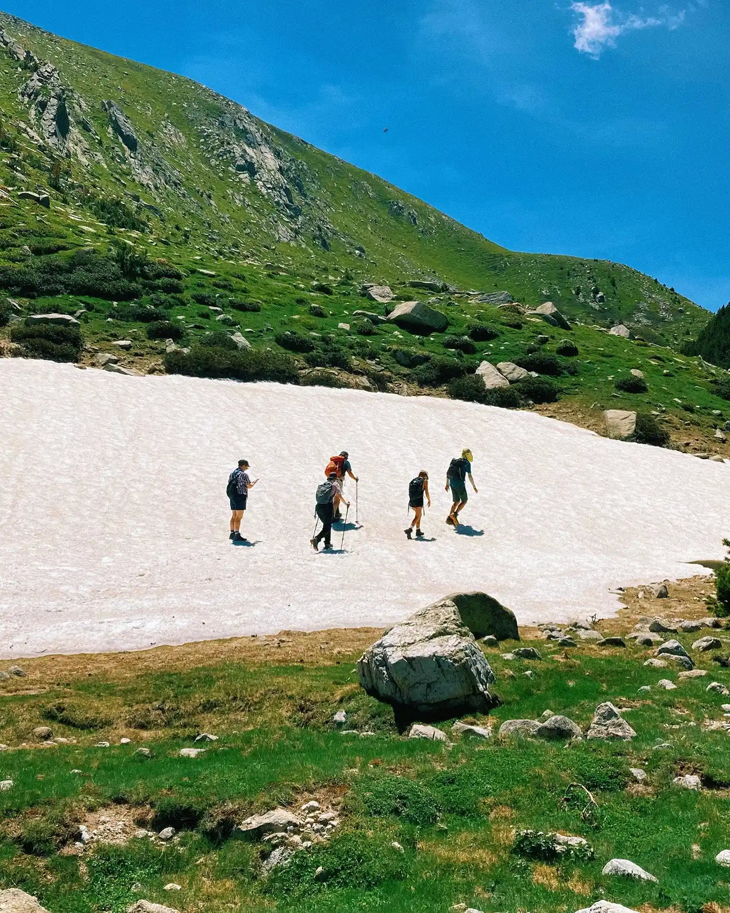 Group of hikers on a snowfield with mountains in the background