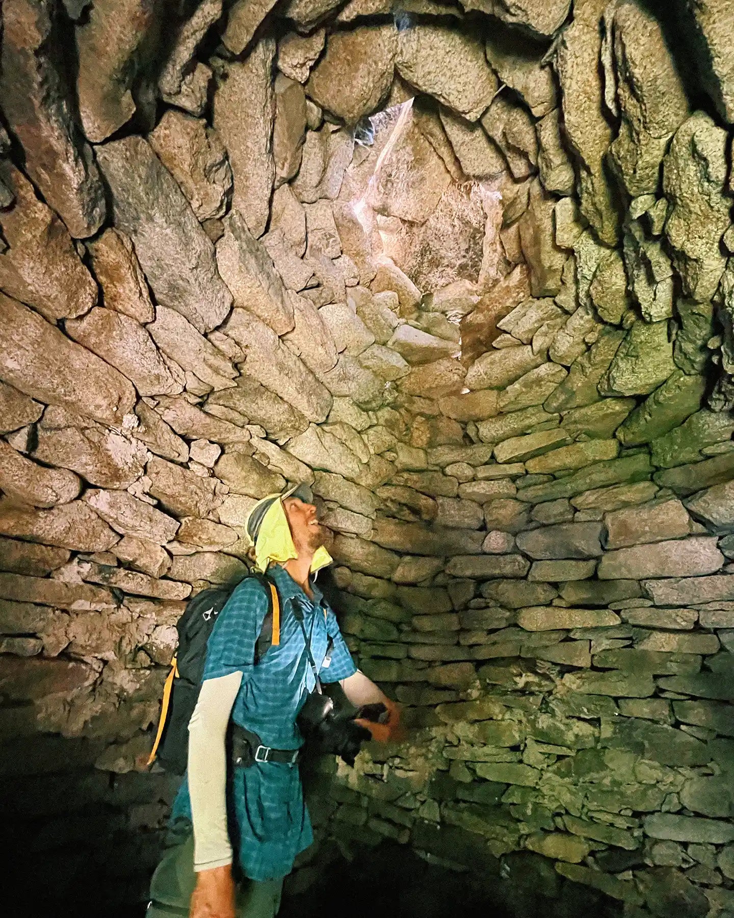 Person exploring a stone archway in a natural setting