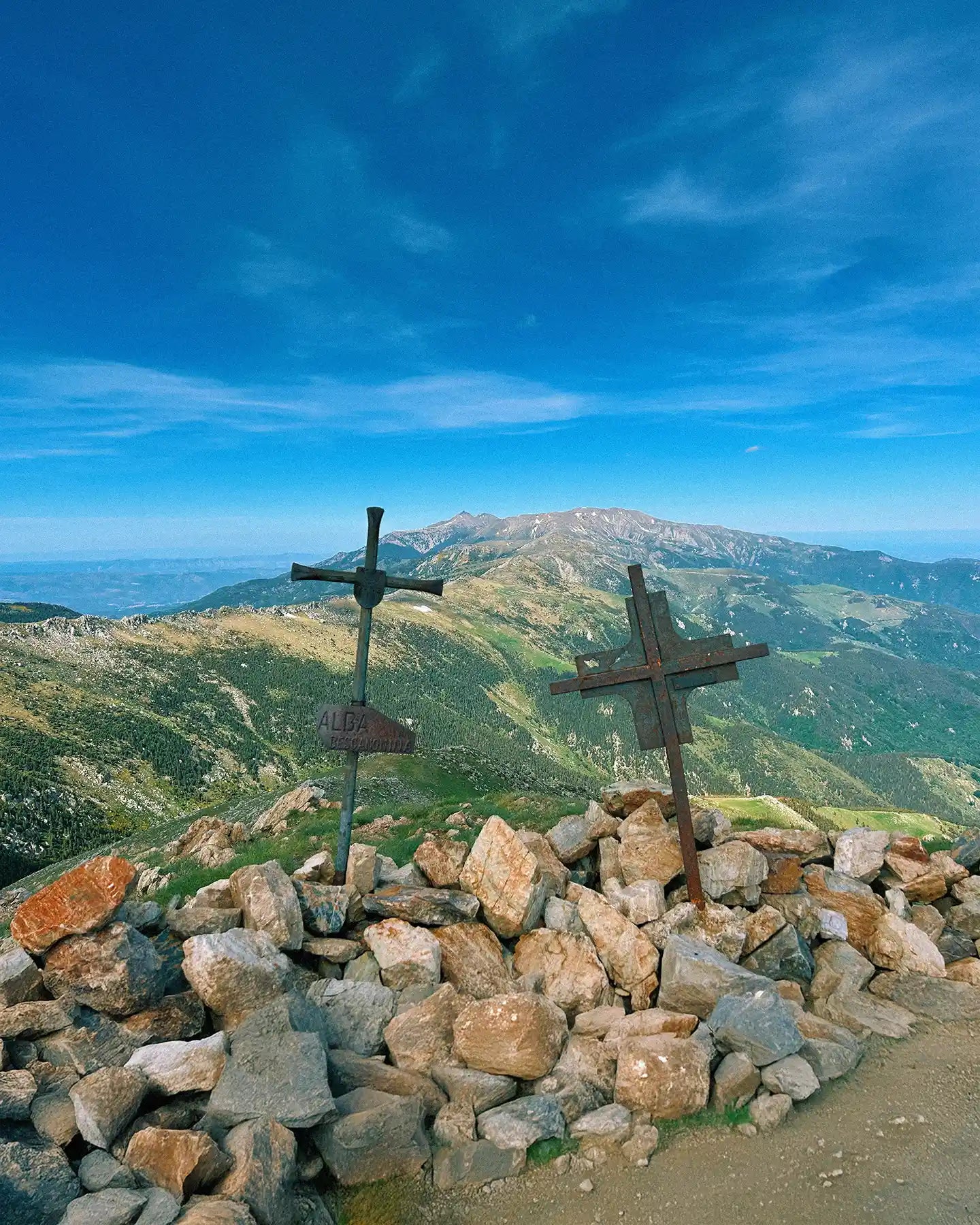 Two crosses on a rocky outcrop with a mountainous landscape in the background