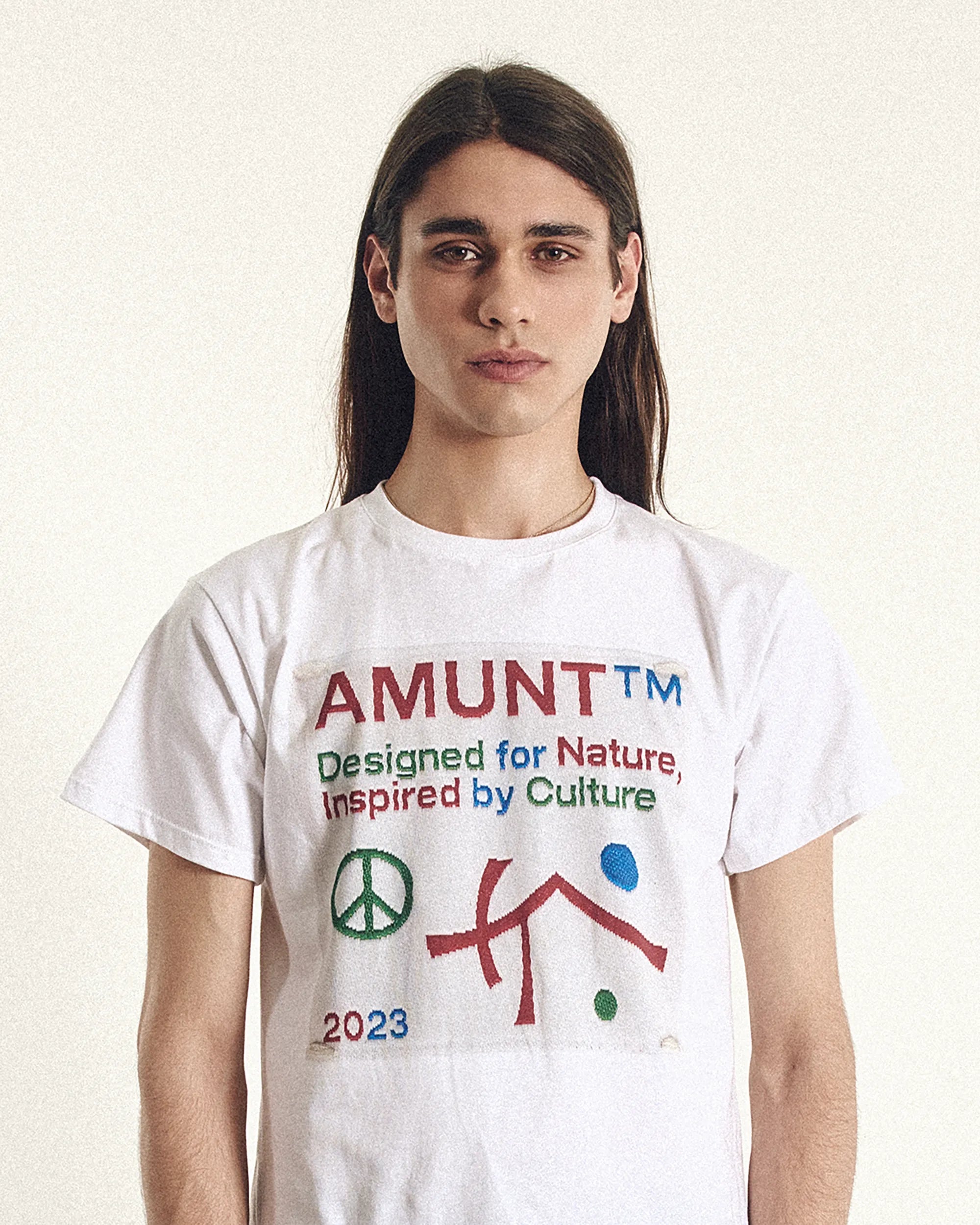 Person wearing a white t-shirt with colorful graphics and text on a plain background