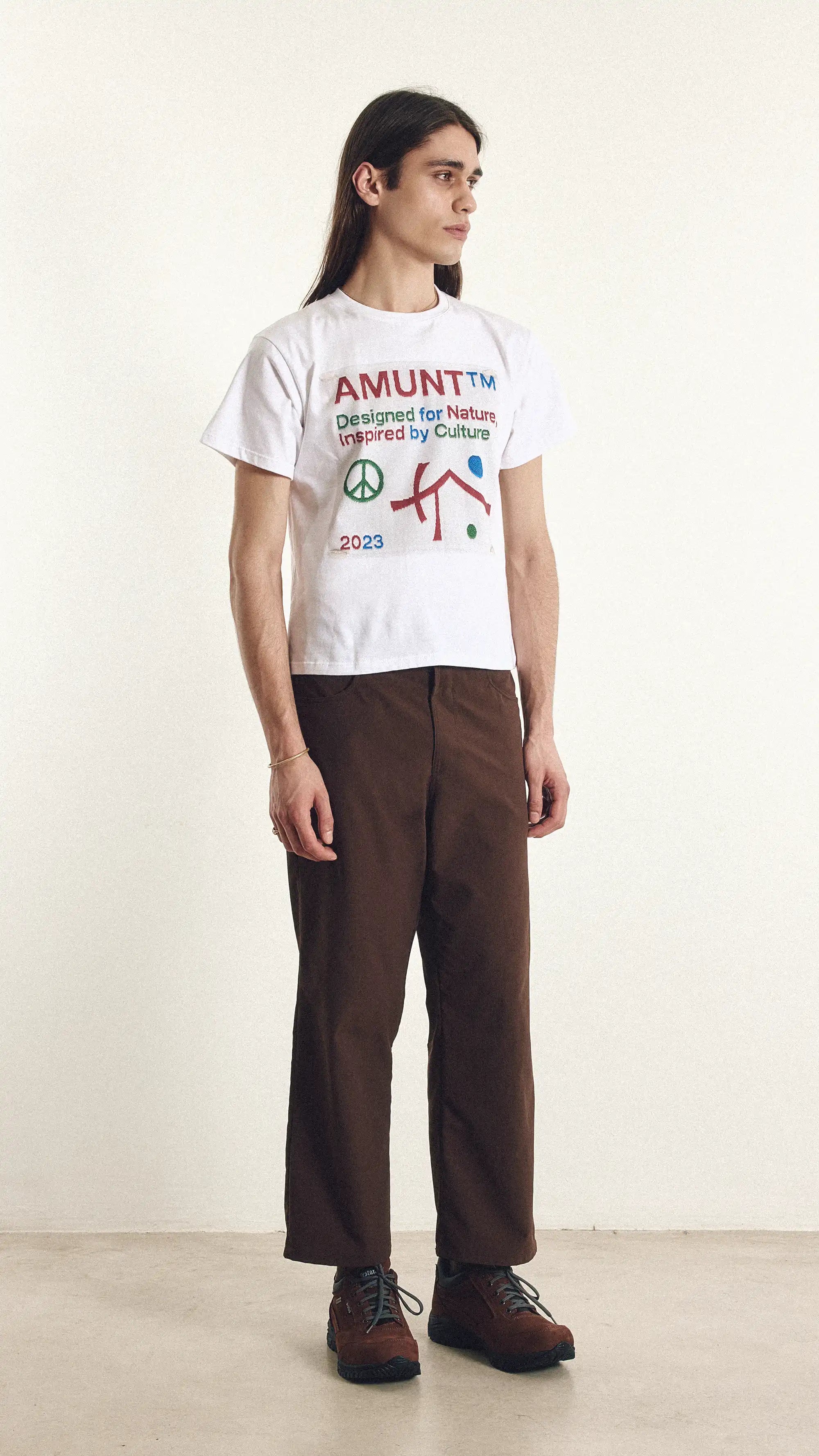 Person wearing a white t-shirt with colorful text and graphics on a plain background