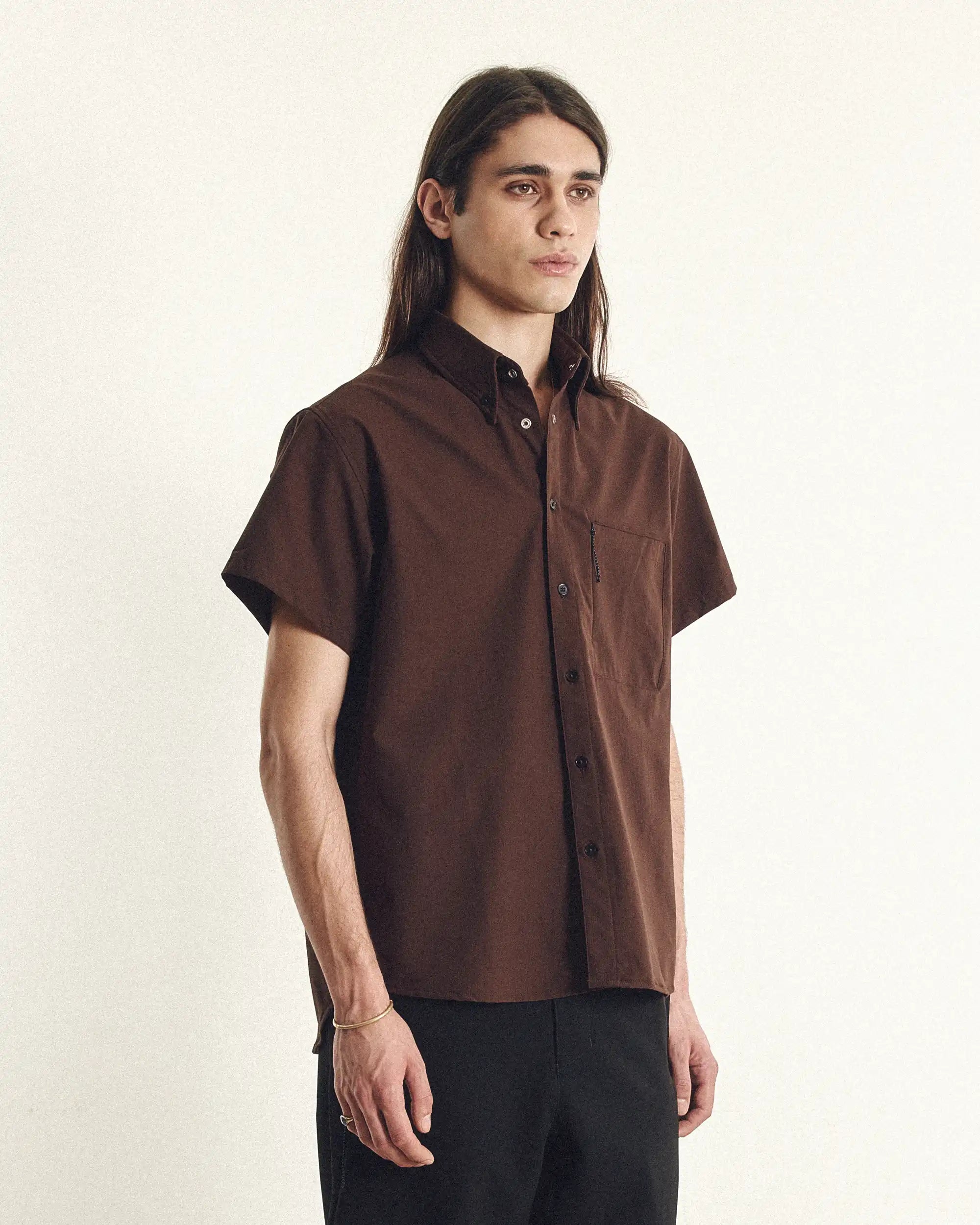 Man wearing a brown short-sleeve shirt against a plain background