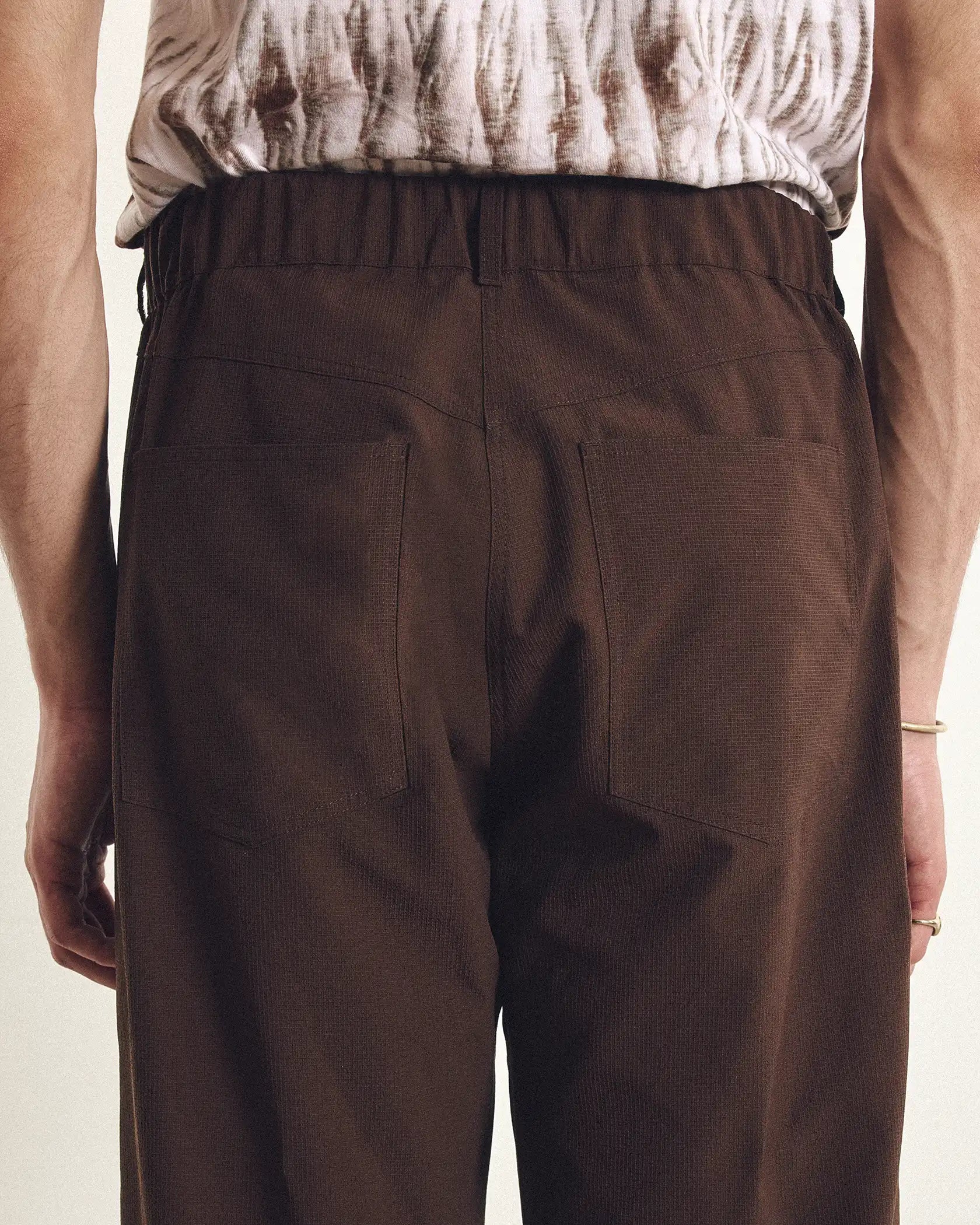 Brown pants worn by a person on a beige background