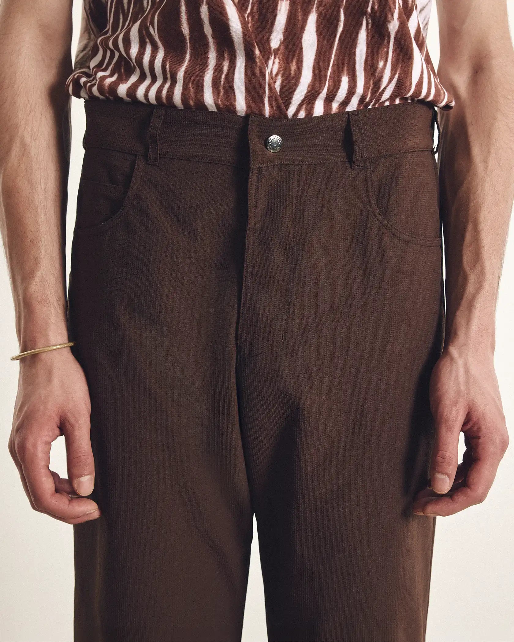 Brown pants worn by a person with a zebra-striped shirt on a plain background