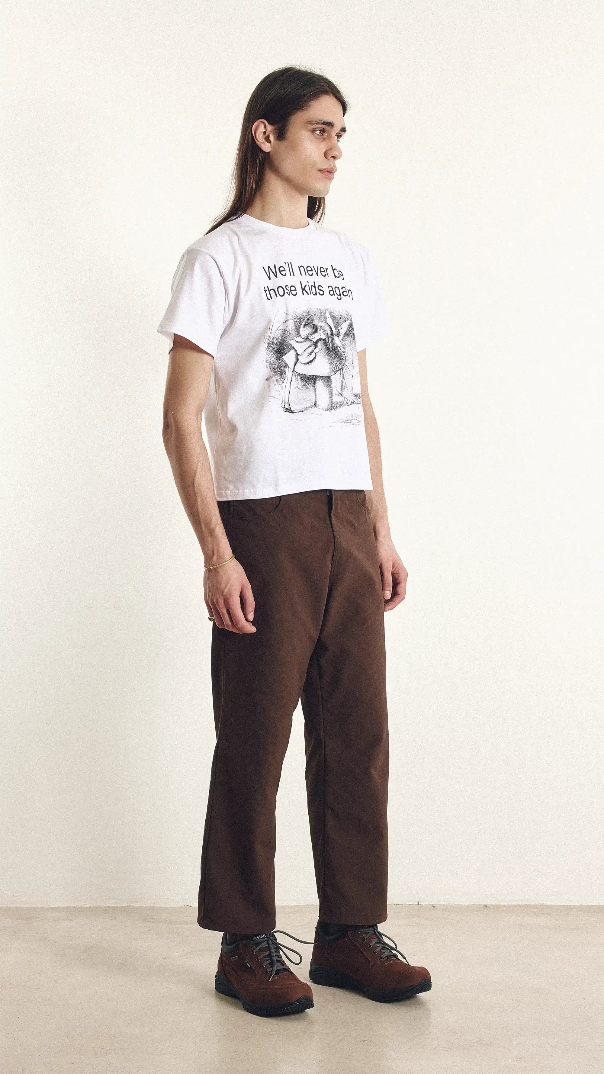 Person wearing a white t-shirt with text and graphics, standing against a plain background