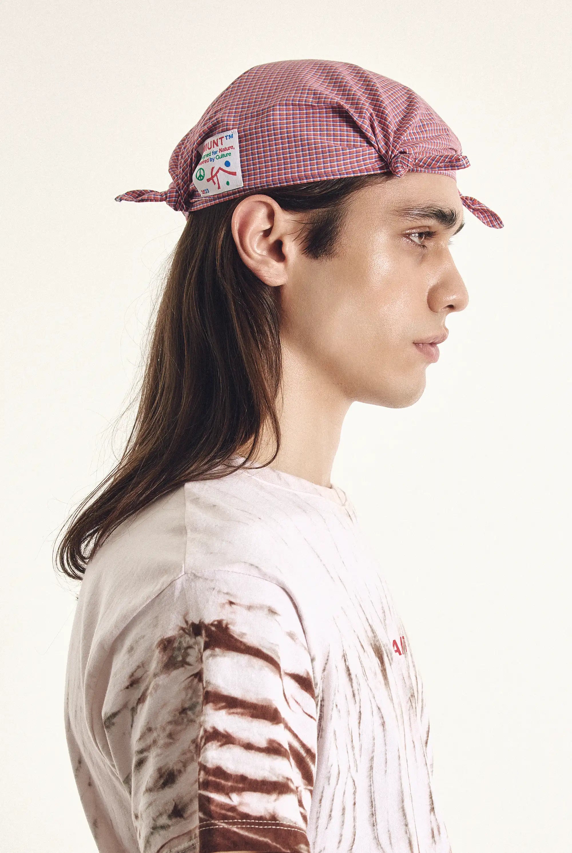 Person wearing a checkered cap with a patch on a white background
