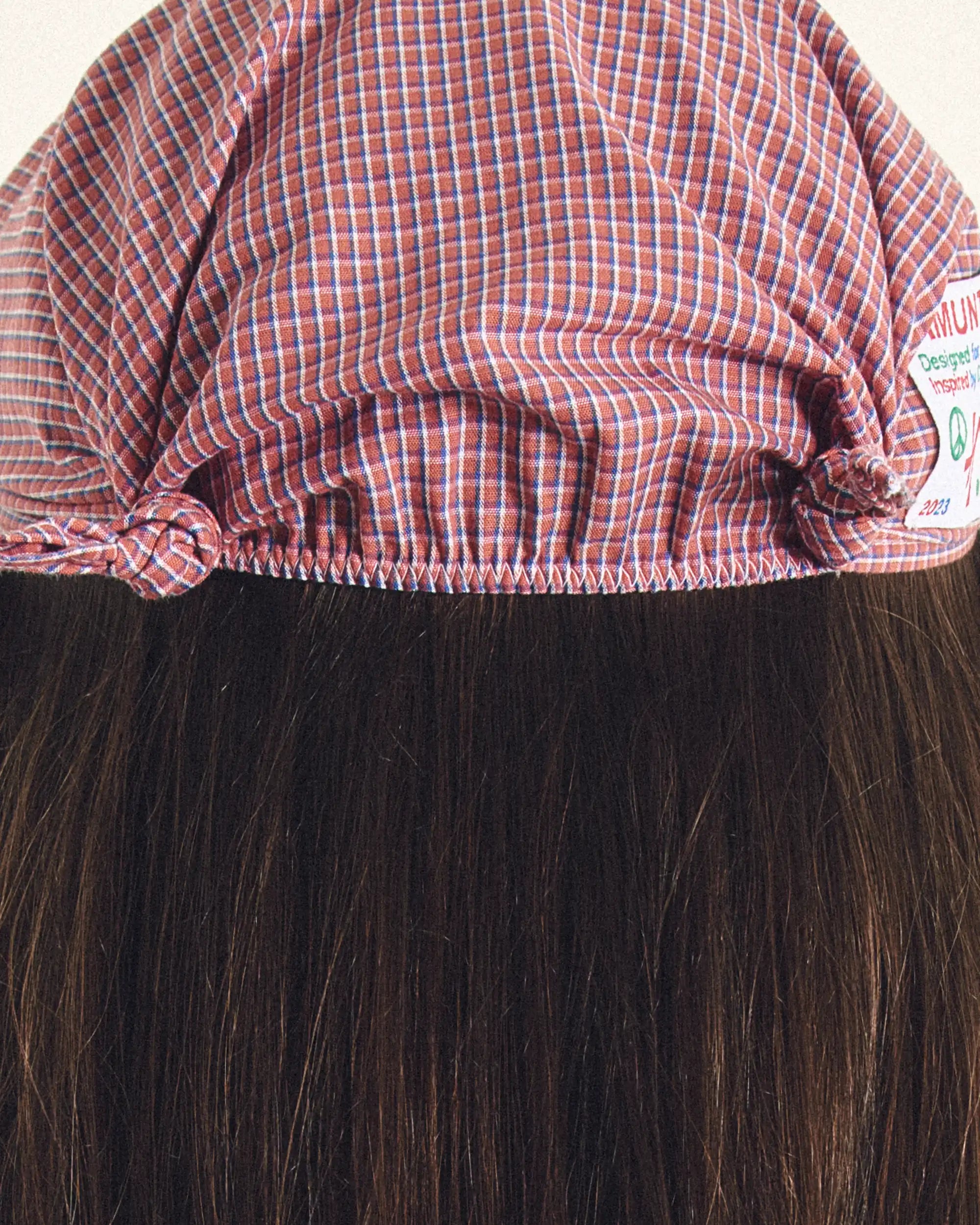 Close-up of a wig with a red and white checkered cap on a white background