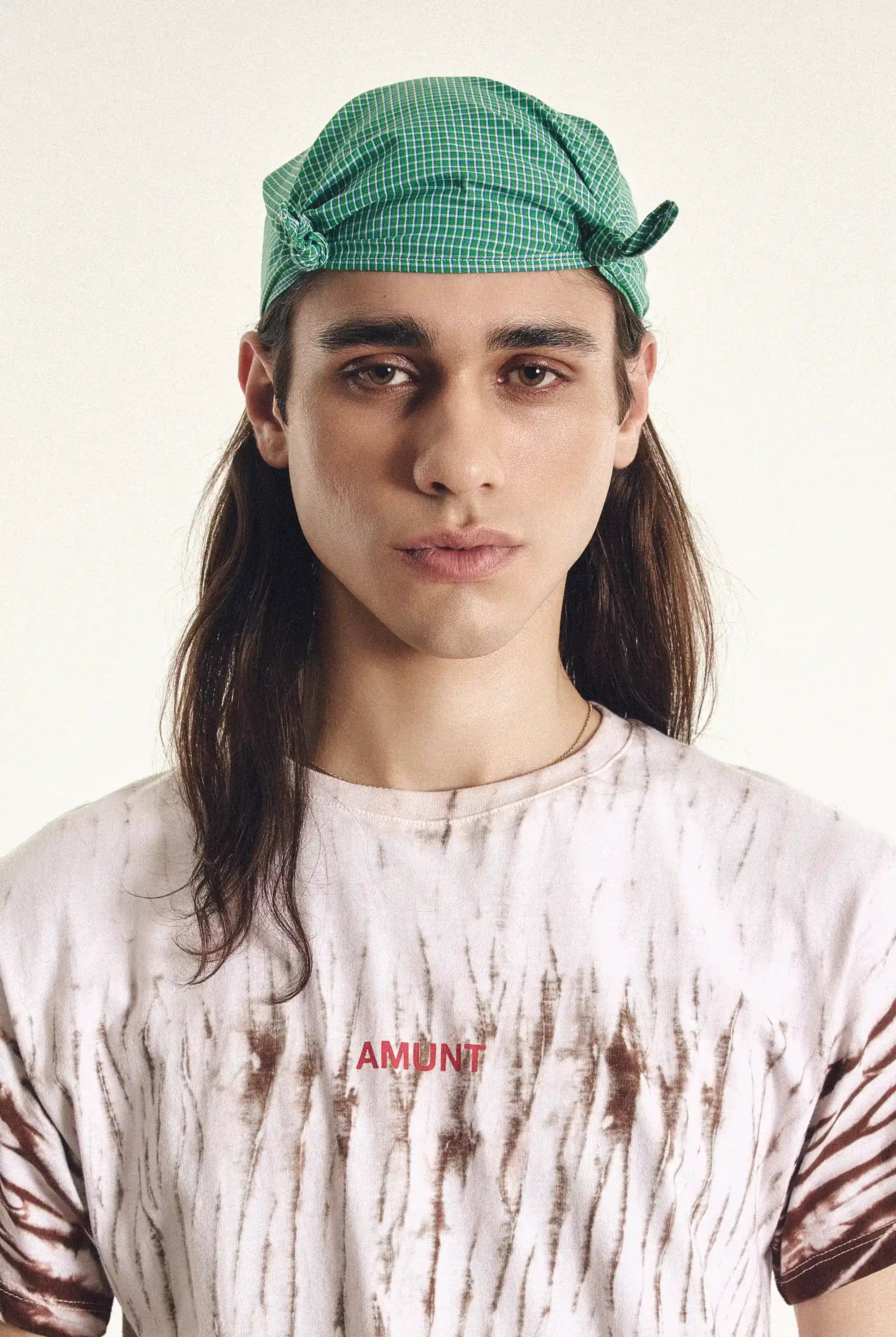 Person wearing a green checkered cap and a tie-dye shirt with 'AMOUR' text.