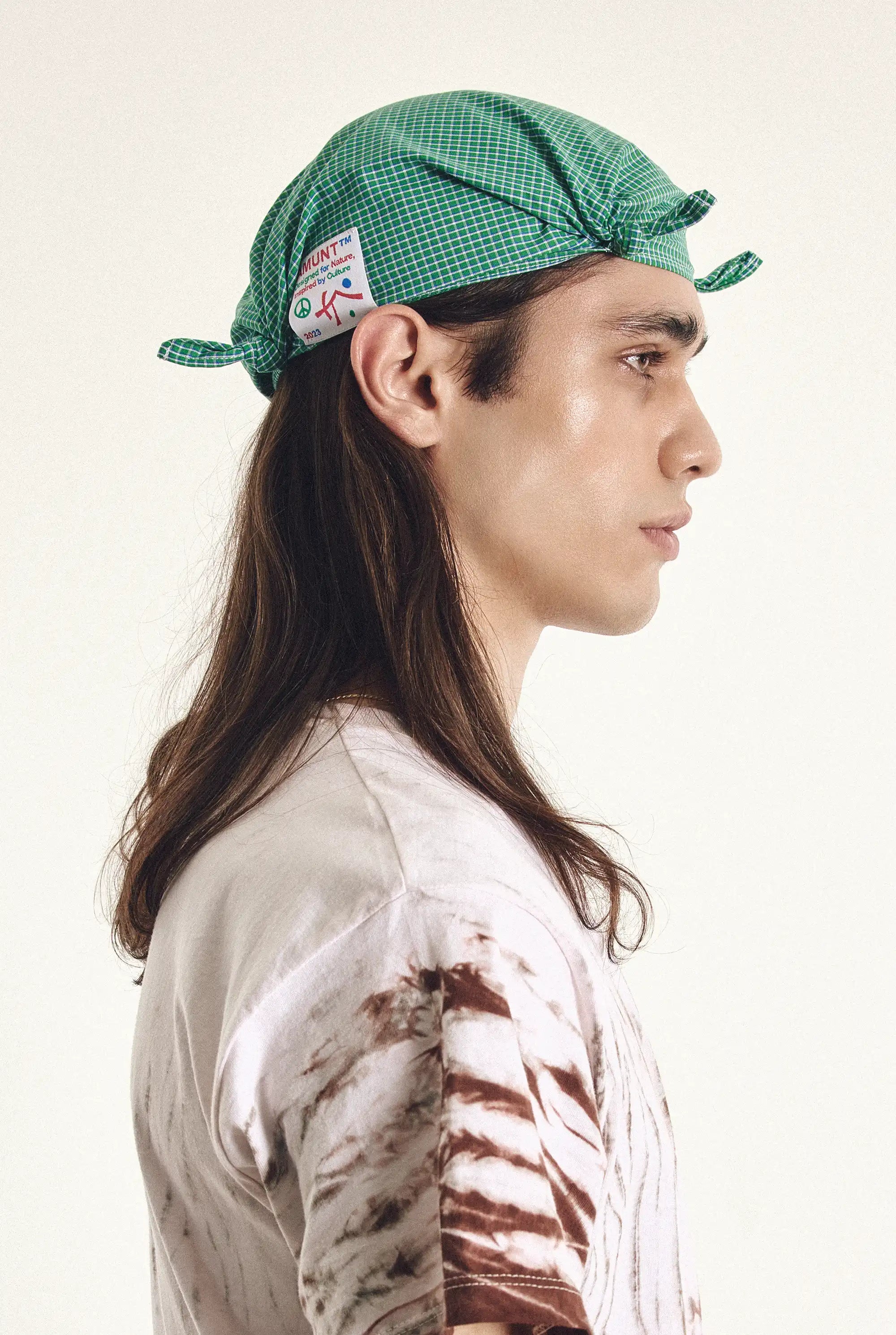 Person wearing a green checkered cap with a logo on a white background