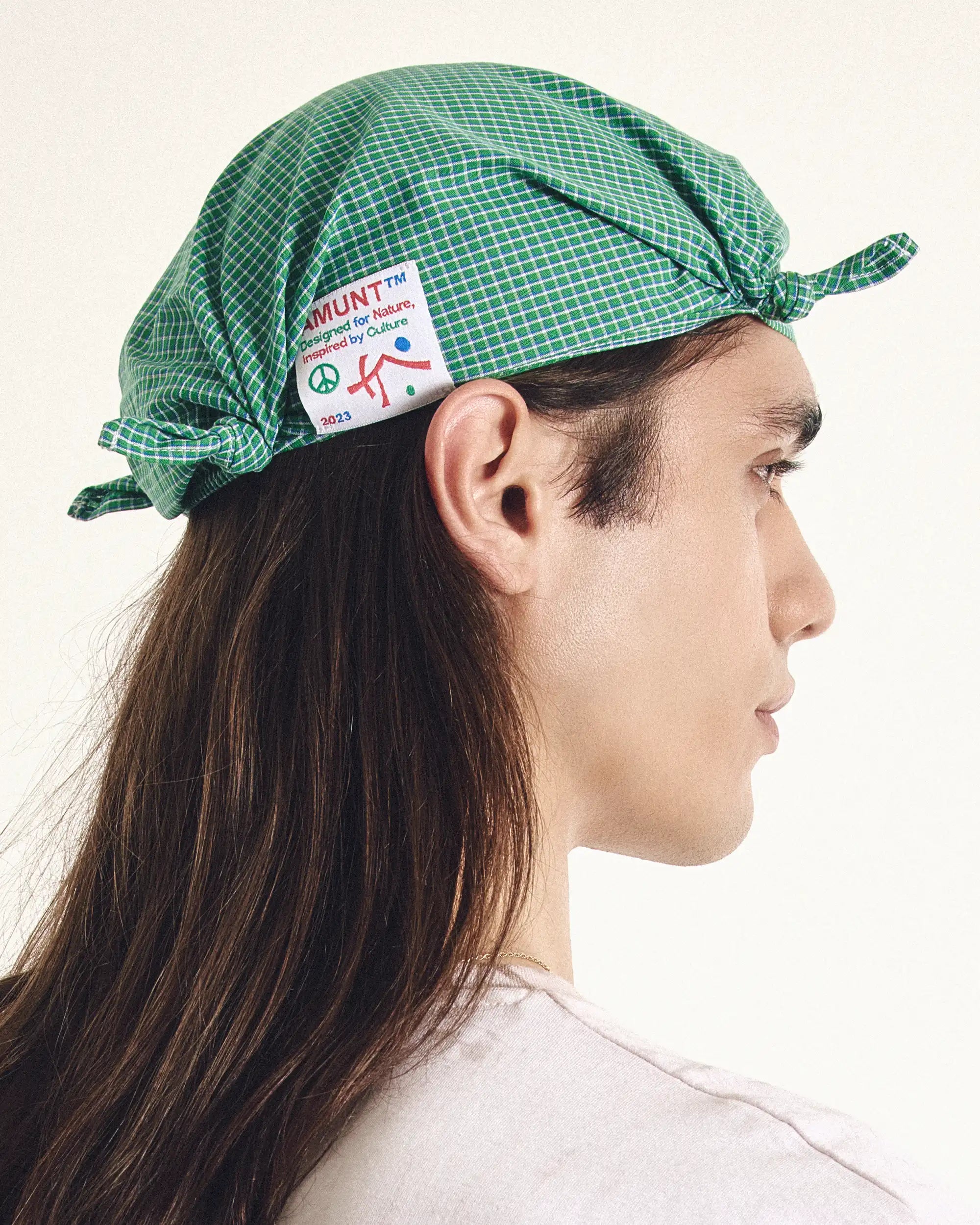 Person wearing a green checkered cap with a visible brand label on a white background