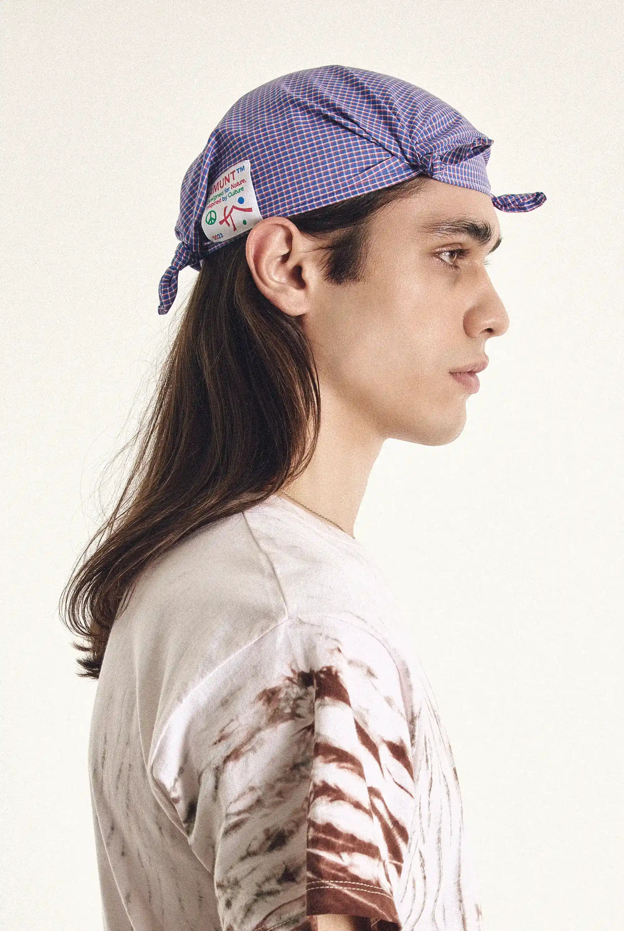 Person wearing a purple checkered cap with a patch on a white background