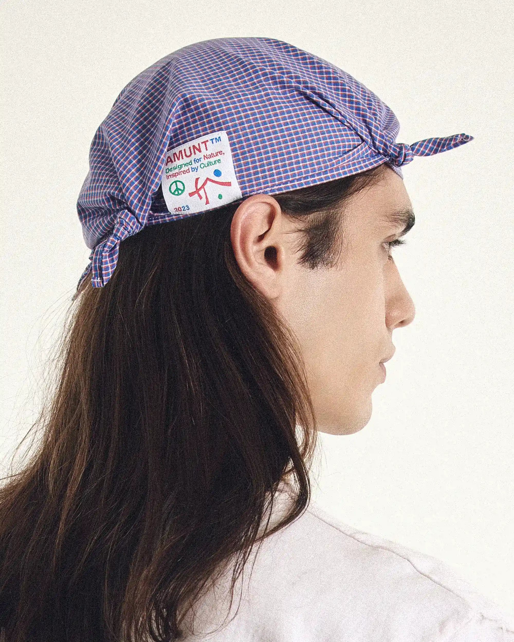 Person wearing a checkered cap with a visible brand logo on a white background