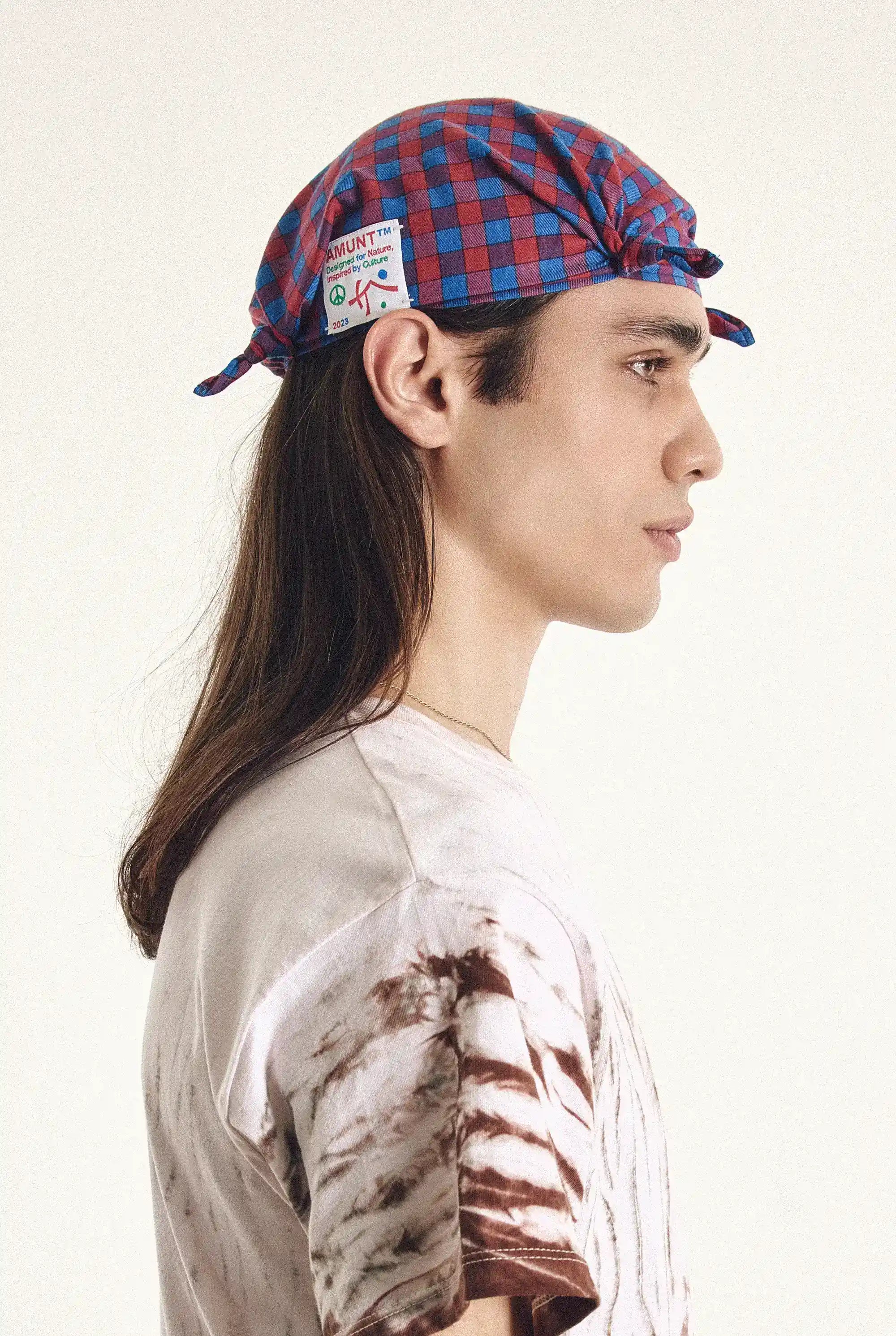 Person wearing a red and blue checkered cap with a patch on a white background