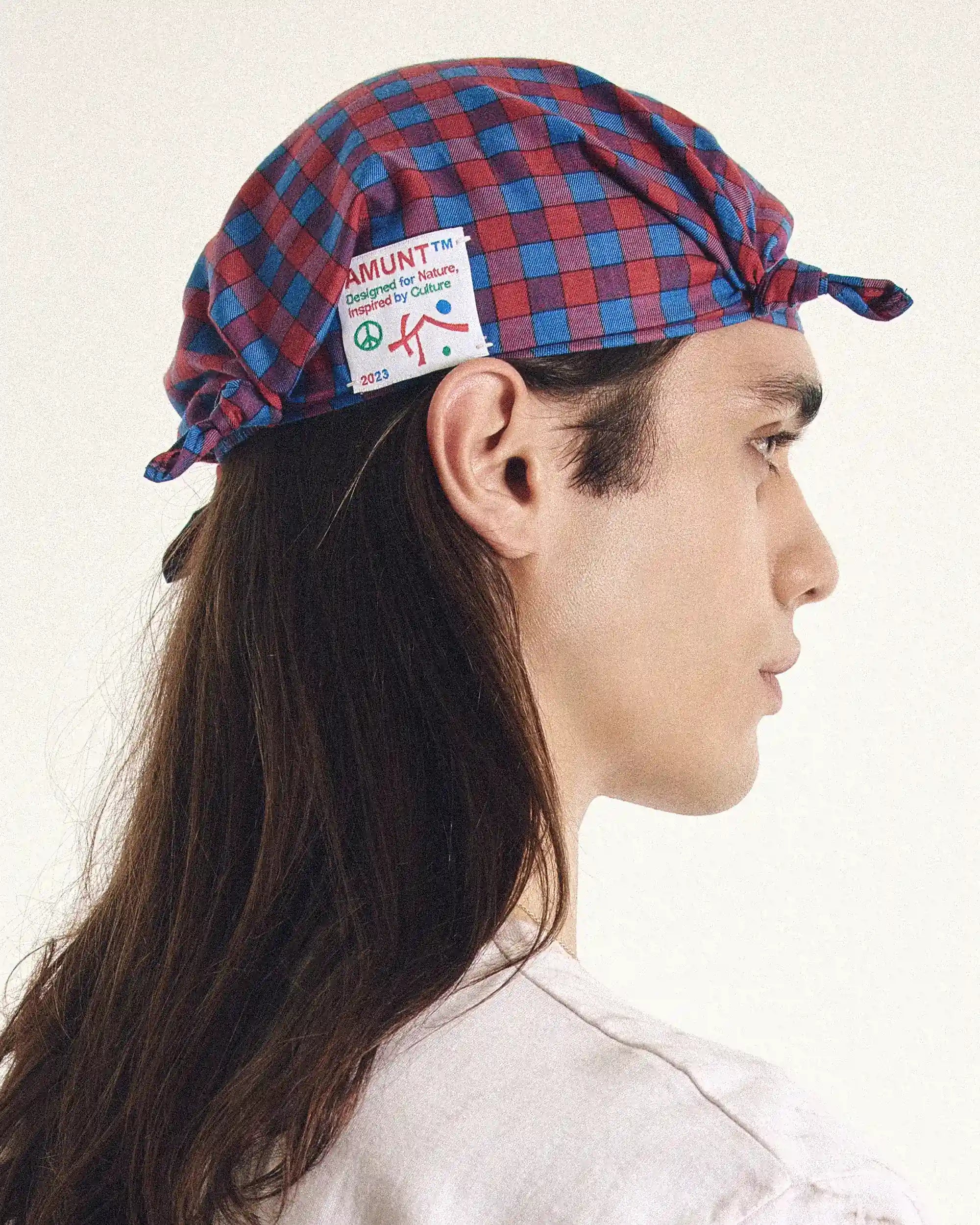 Person wearing a red and blue checkered cap with a visible brand logo.