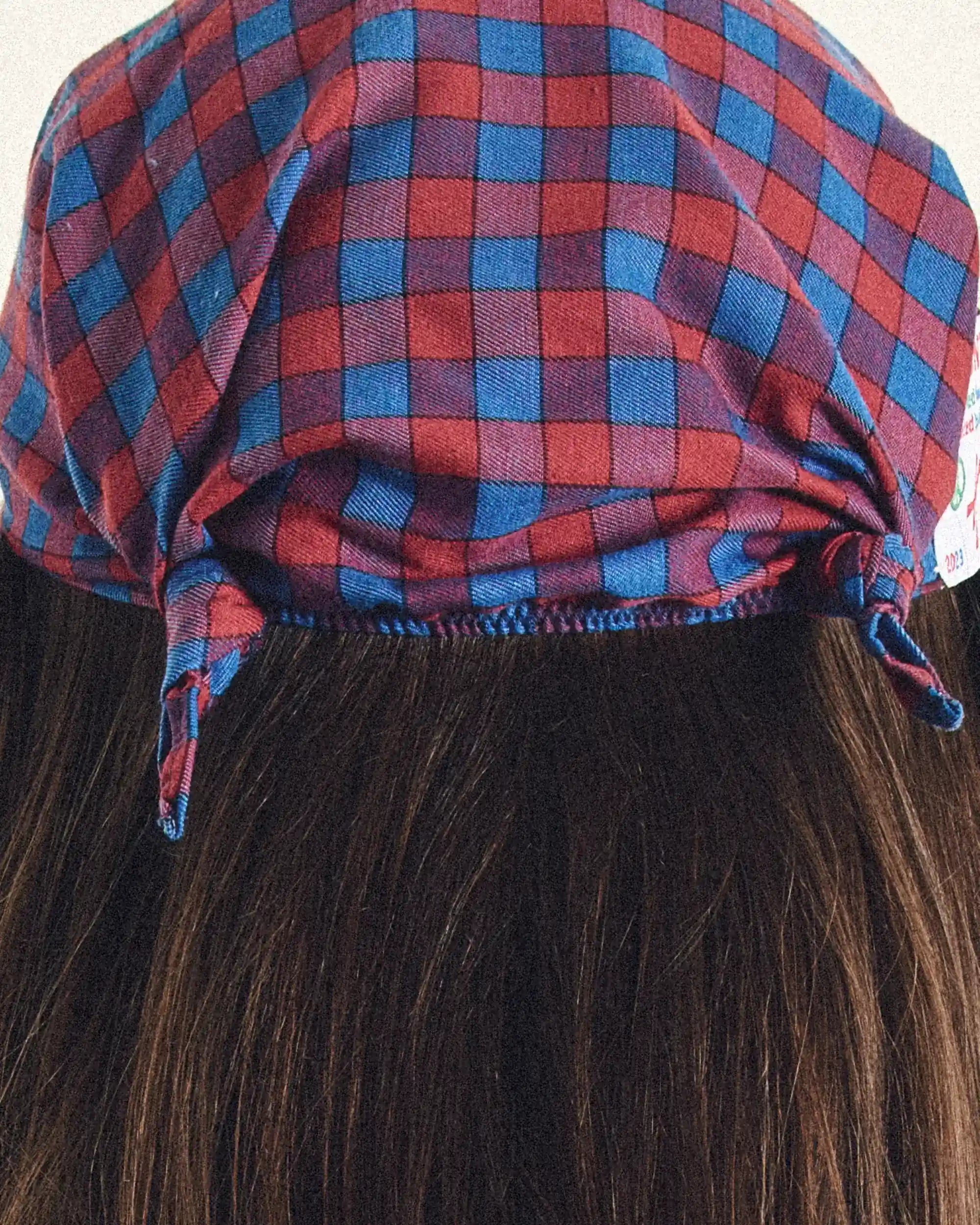 Red and blue checkered cap on dark hair