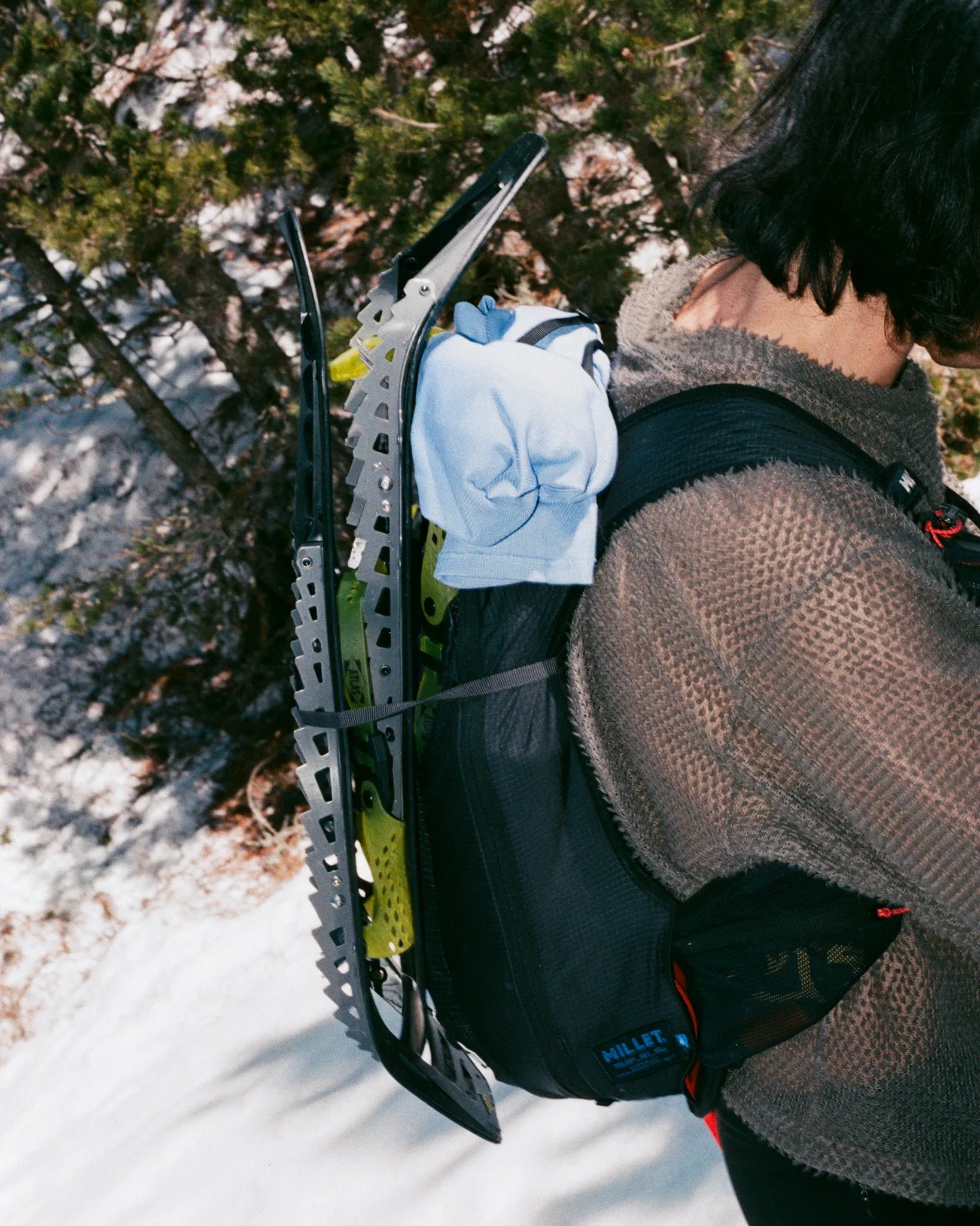 Person wearing a snowmobile helmet with a snowmobile on a snowy trail