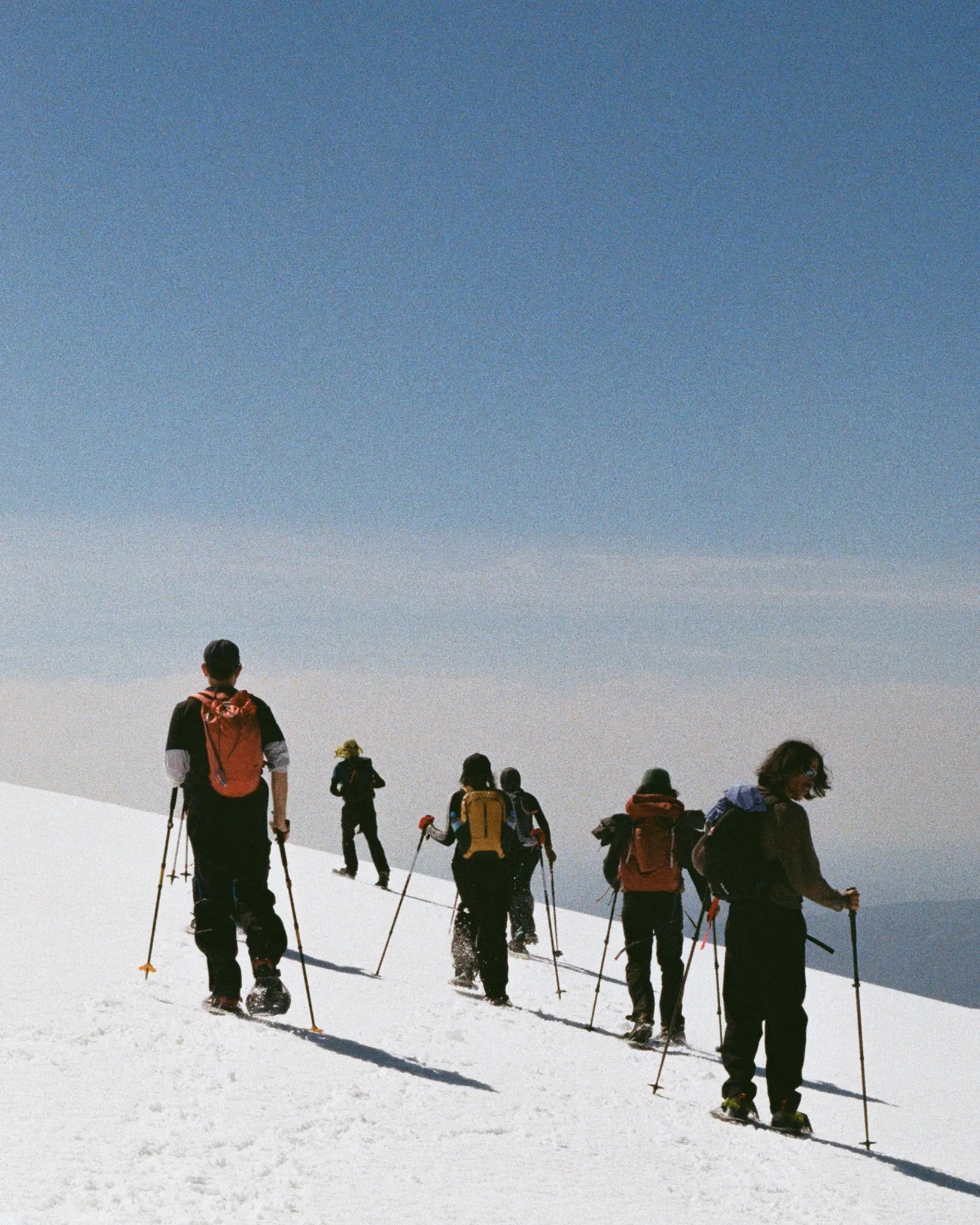 Group of skiers on a snow-covered slope with a clear blue sky.