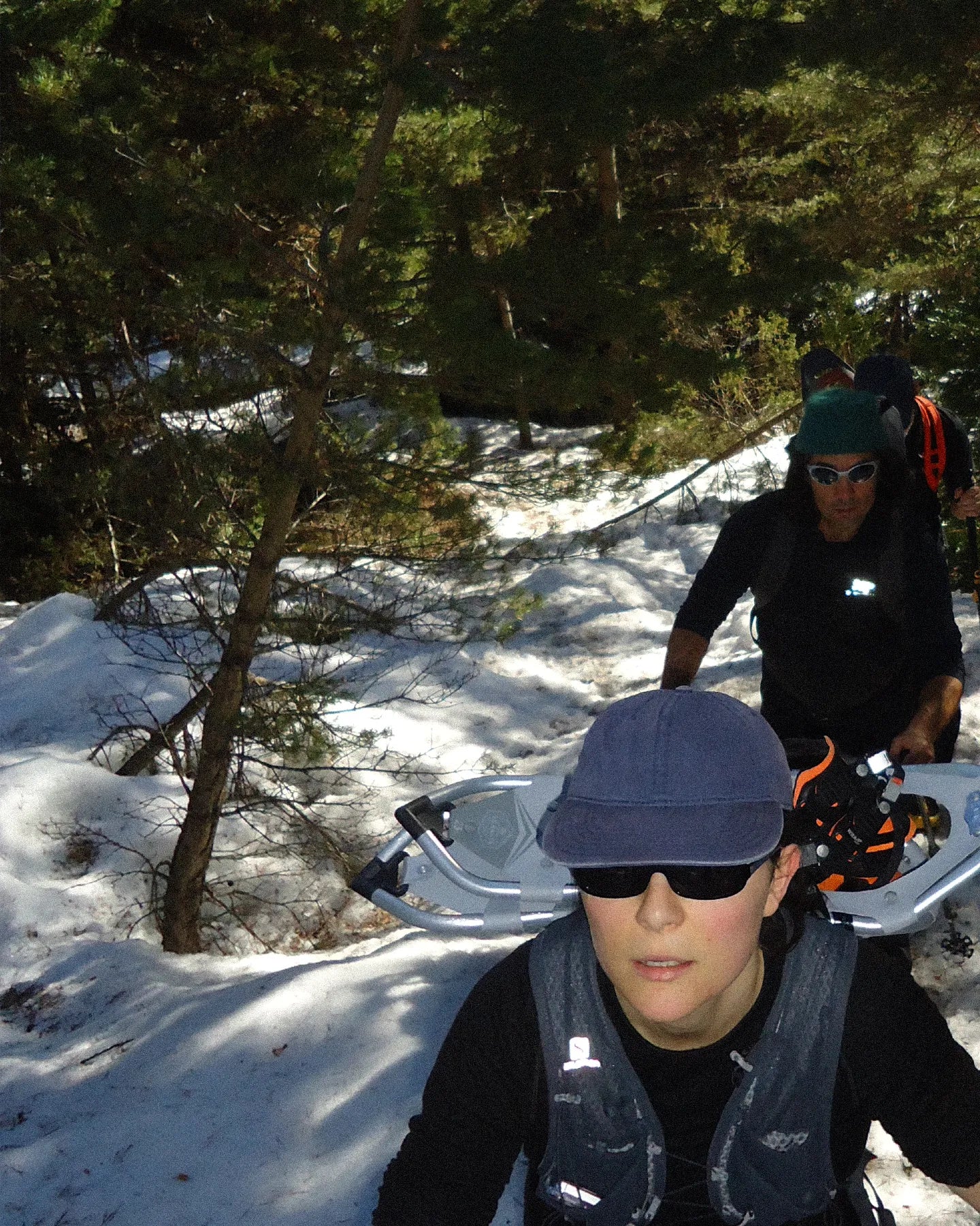 Two people in a snowy forest with snowmobiles