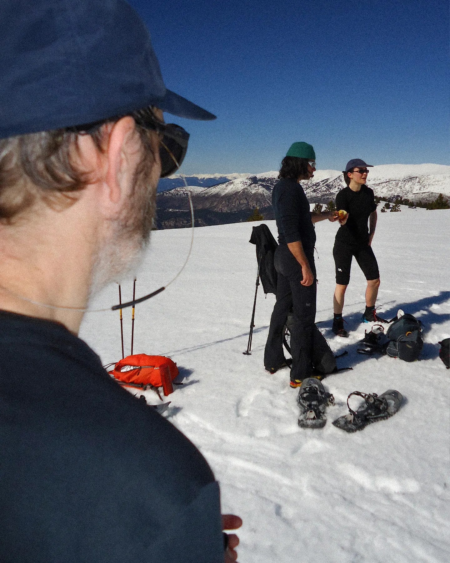 Group of people snowshoeing with equipment on a snowy landscape.