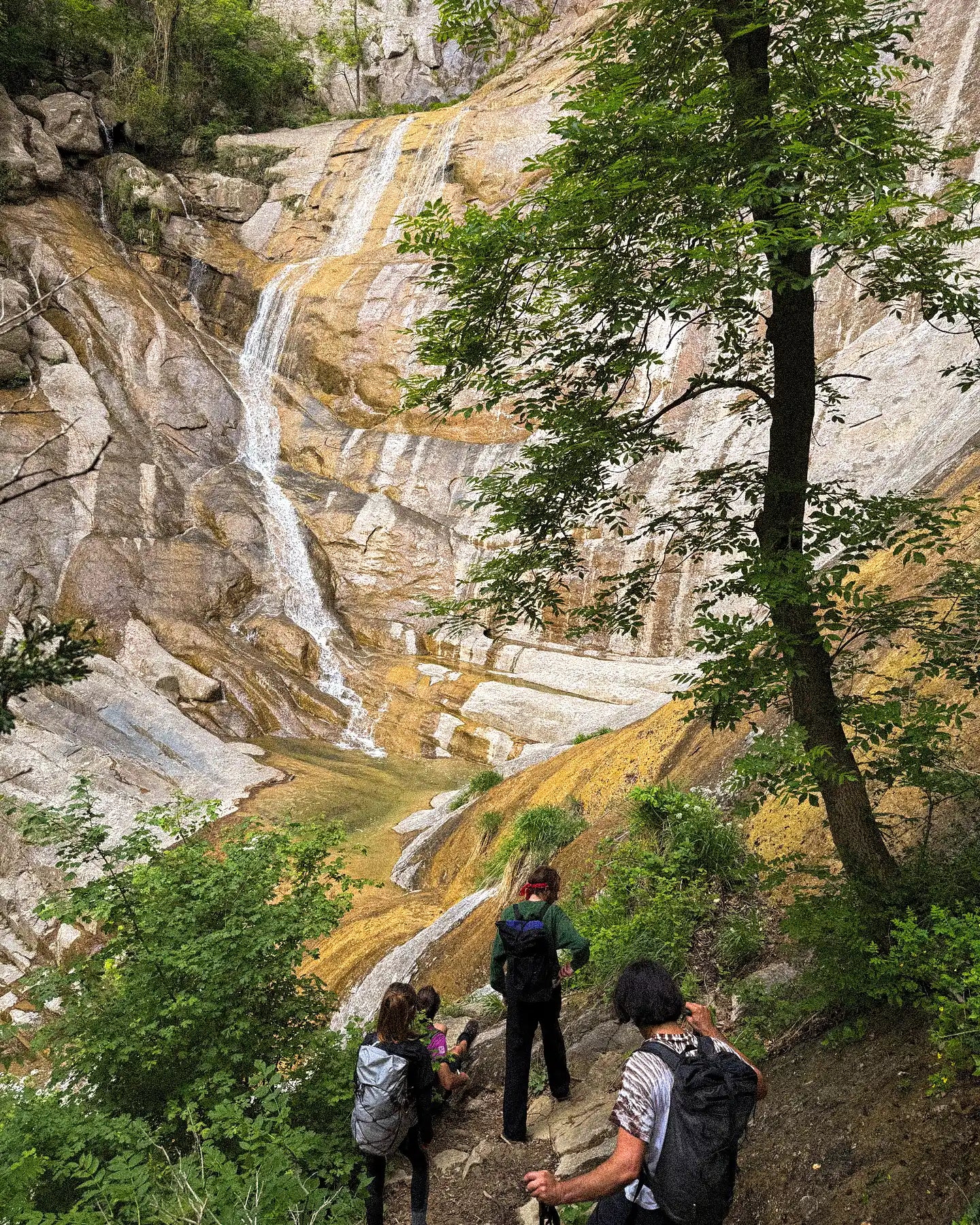Hikers exploring a mountainous area with a waterfall in the background
